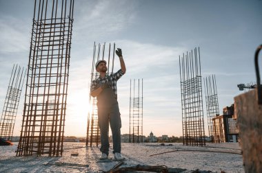 Eller yukarı. Emirleri vermek. Gündüz vakti inşaatta çalışan bir adam var..