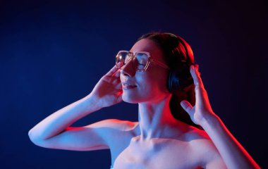 Kulaklık kullanarak müziğin tadını çıkarıyorum. İçerideki neon ışıkta duran genç bir kadının portresi..