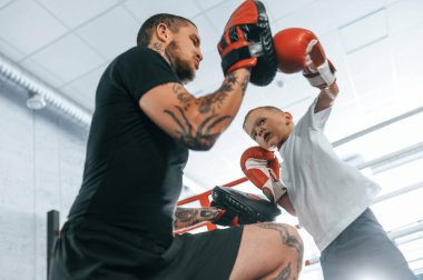 Yumruk atmayı öğretiyorum. Koç, çocuğun tekniklerini kapalı mekanda gösteriyor..