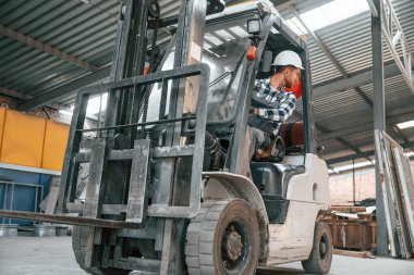 Forkliftin içinde. Üniformalı fabrika çalışanı içeride..