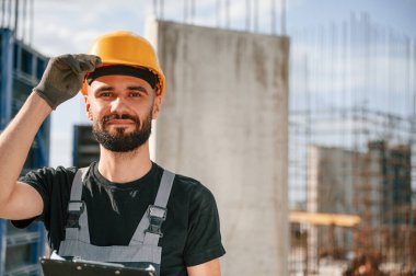 Not defteriyle bir kamera için poz vermek. Güzel bir portre. Üniformalı adam inşaat alanında çalışıyor..