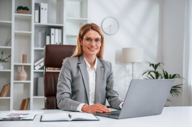 Laptop kullanıyorum. İş kadını resmi giysileri ofiste çalışıyor..