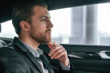 Modern otomobilde duran resmi iş kıyafetleri içindeki bir adamın portresi..