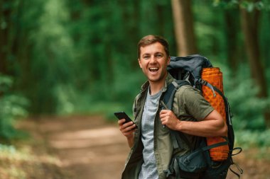 Akıllı telefon ellerindeyken. Yaz ormanında bir turist. Keşif ve eğlence kavramı.