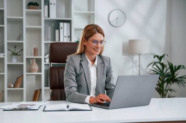 Laptop kullanıyorum. İş kadını resmi giysileri ofiste çalışıyor..