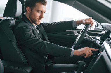 Düğmeleri çeviriyorum. Resmi iş elbiseli adam modern otomobilde oturuyor..