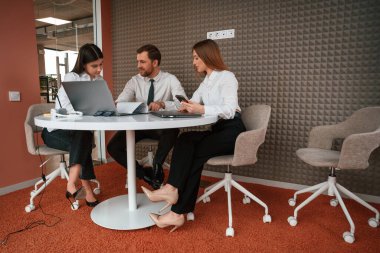 Ofiste üç iş adamı birlikte çalışıyor..