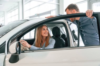İçeriyi deniyorum. Resmi elbiseli adam elektrikli arabalı kadın müşteriyle birlikte..
