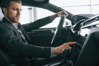 Test sürüşü. Resmi iş elbiseli adam modern otomobilde oturuyor..