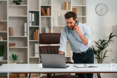 Telefonla. Resmi kıyafetli doktor dolapta çalışıyor..