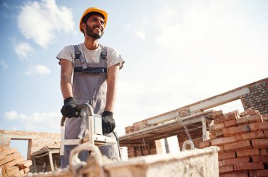 Betonu karıştırmak için bir aletle. Yakışıklı Hintli adam şantiyede..
