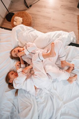 Yatakta birbirimizi gıdıklıyoruz. İki küçük kız evcil odada oynuyorlar ve eğleniyorlar..