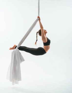 Esnek vücut tipi. Beyaz arka planda uçan yoga yapan genç ve güzel bir kadın..