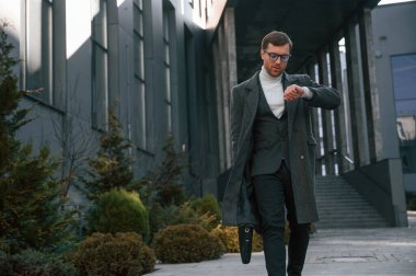 Saate bakıyorum. Resmi kıyafetli yakışıklı dışarıda, iş binasının yanında..