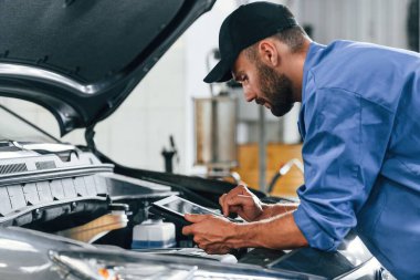 Tablet kullanıyorum. Otomobil tamircisi garajda çalışıyor. Onarım servisi.