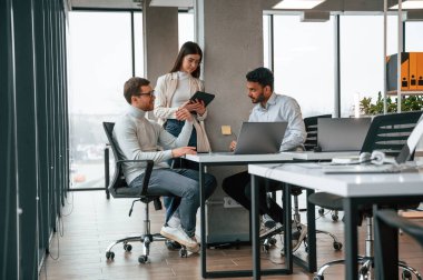 Bilgisayarlı masanın yanında. Erkekler ve kadınlar ofiste birlikte çalışıyorlar..