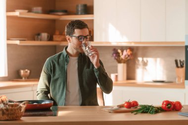 Bir bardak suyla. Yakışıklı adam gündüz vakti mutfakta olur..