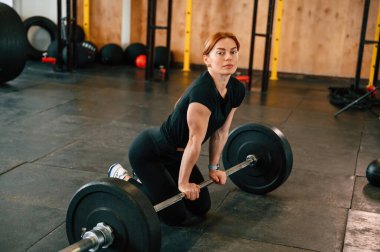 Halterin üzerine yaslan. Yere yatın. Güzel, güçlü kadın spor salonunda..