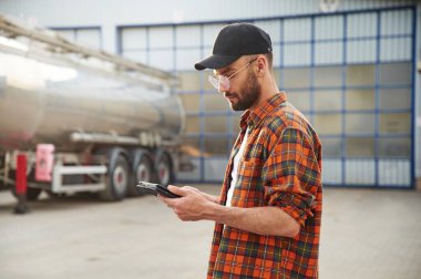 Tableti tutuyorum. Gündelik giysiler içindeki genç kamyon şoförü..