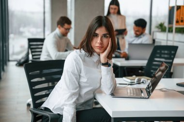 Göz kamaştırıcı kadın iş arkadaşlarının önünde. Ofiste birlikte çalışan dört kişi var..