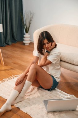 Yerdeki dizüstü bilgisayara bakıyorum. Günlük giysiler içinde güzel bir kadın evde, yurt odasında..