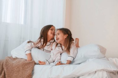 Yatağa uzanıyordu. İki küçük kız evcil odada oynuyorlar ve eğleniyorlar..