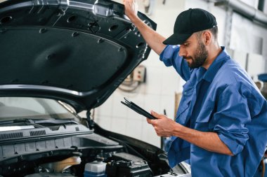 Kaput açıldı. Otomobil tamircisi garajda çalışıyor. Onarım servisi.