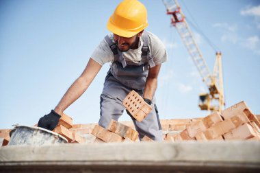 Mavi gökyüzü ve turna arkada. Yakışıklı Hintli adam şantiyede..