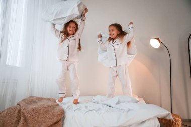 Yurt içi odada, yatağın üstünde. Yastık savaşı oynuyoruz. İki küçük kız yurt odasında birlikte eğleniyorlar..