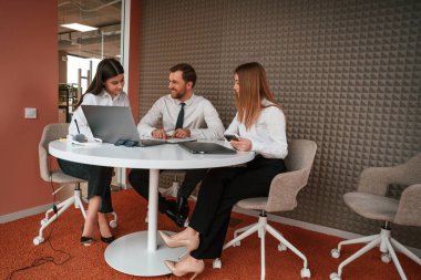 Bilgisayarlı masanın yanında. Ofiste üç iş adamı birlikte çalışıyor..