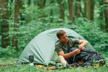 Yeşil renkli çadır arkada. Yaz ormanında bir turist. Keşif ve eğlence kavramı.