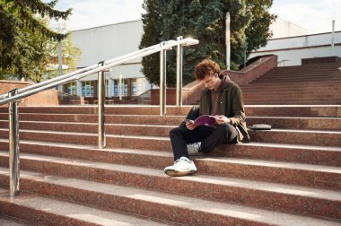 Merdivenlerde, kitap okuyordum. Kıvırcık saçlı genç öğrenci üniversiteye yakın bir yerde..