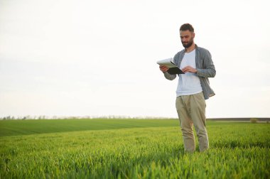 Elinde not defteriyle. Yakışıklı genç adam tarım alanında..