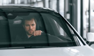 Ciddi bir yüz ifadesi. Arabayı sürüyorum. Resmi iş elbiseli adam modern otomobilde oturuyor..