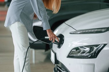 Şarj aletini takıyorum. Elektrikli arabalı bir kadının yakın görüntüsü.