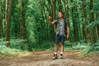Akıllı telefon ellerindeyken. Yaz ormanında bir turist. Keşif ve eğlence kavramı.