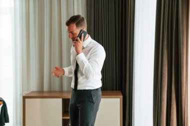 İş görüşmesi, telefonla konuşmak. Adam içeride, otel odasında..