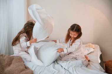 Yastıkları tutmak ve oynamak. İki küçük kız yurt odasında birlikte eğleniyorlar..
