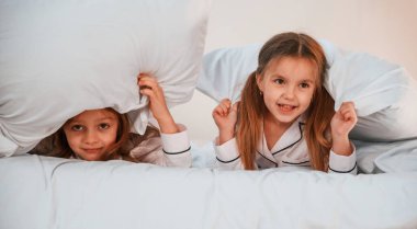 Çocuklar yatağa uzanıyorlar. İki küçük kız evcil odada oynuyorlar ve eğleniyorlar..