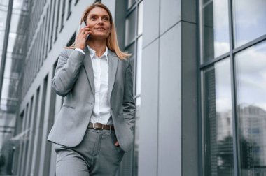 Telefonun başındaki konuşma. Resmi giysili kadın iş binasının yakınında dışarıda..