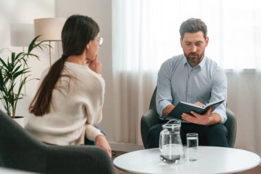 Bir psikologla seans. Bir kadınla. Resmi kıyafetli doktor dolapta çalışıyor..