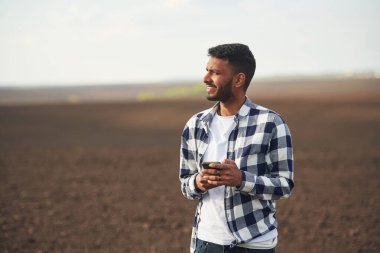 Akıllı telefon ellerde. Tarım tarlası. Yakışıklı Hintli adam..