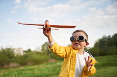 Küçük çocuk yaz sahasında oyuncak uçakla oynuyor..