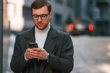 Resmi giyinmiş yakışıklı bir adamın portresi iş binasının yakınındadır..