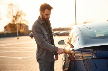 - Otoparkta. Otomobili şarj ediyorum. Adam dışarıda elektrikli arabasının yanında duruyor..