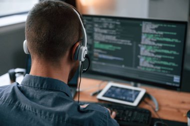 Yazılım geliştiricisi kod yazıyor. Resmi kıyafetli adam modern ofiste çalışıyor. Bilgisayar kullanılıyor.