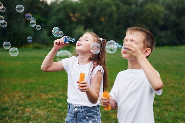 Beautiful bubbles. Kids are having fun on the field at daytime together.