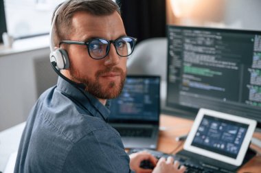 Yazılım geliştiricisi kod yazıyor. Resmi kıyafetli adam modern ofiste çalışıyor. Bilgisayar kullanılıyor.