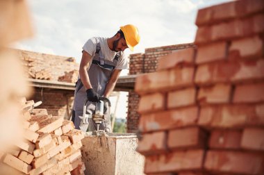 Betonu karıştırmak için bir aletle. Yakışıklı Hintli adam şantiyede..