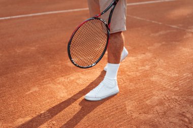 Manzarayı kapat. Raketle. Genç adam güneşli bir günde tenis kortunda..